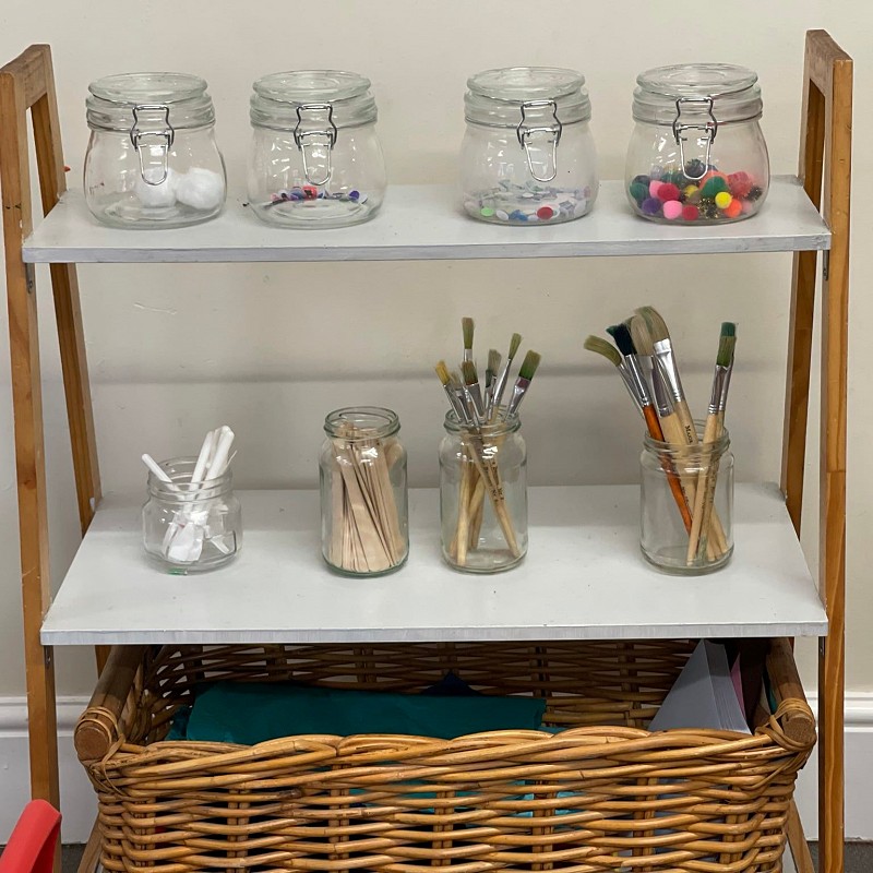 Jars on a shelf containing craft supplies